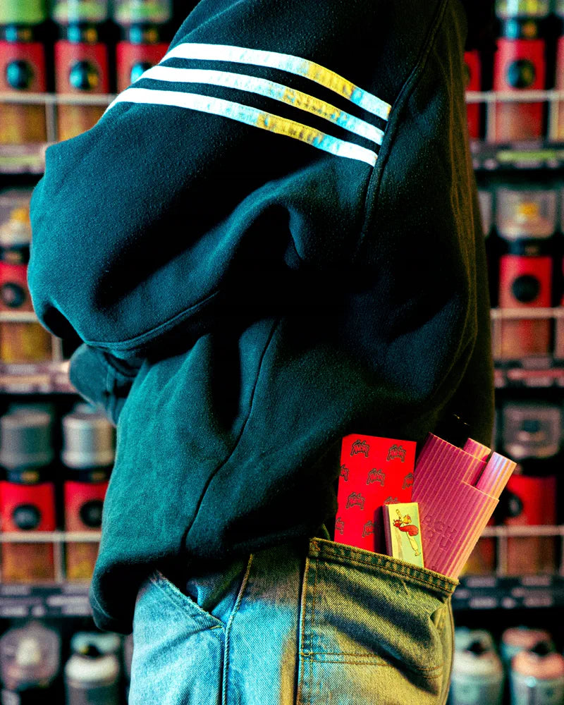 Kailar Papers stecken in einer Gesäßtasche, dahinter ein Kiosk-Regal